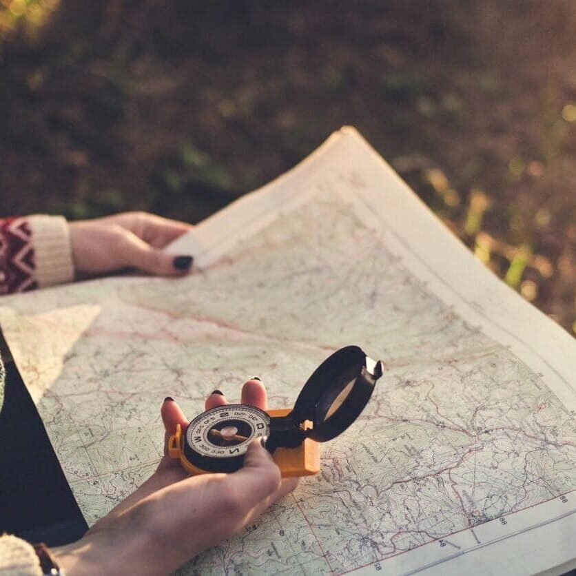 A person holding a compass and looking at a map.